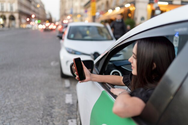 Woman looks out of car window and looks at phone